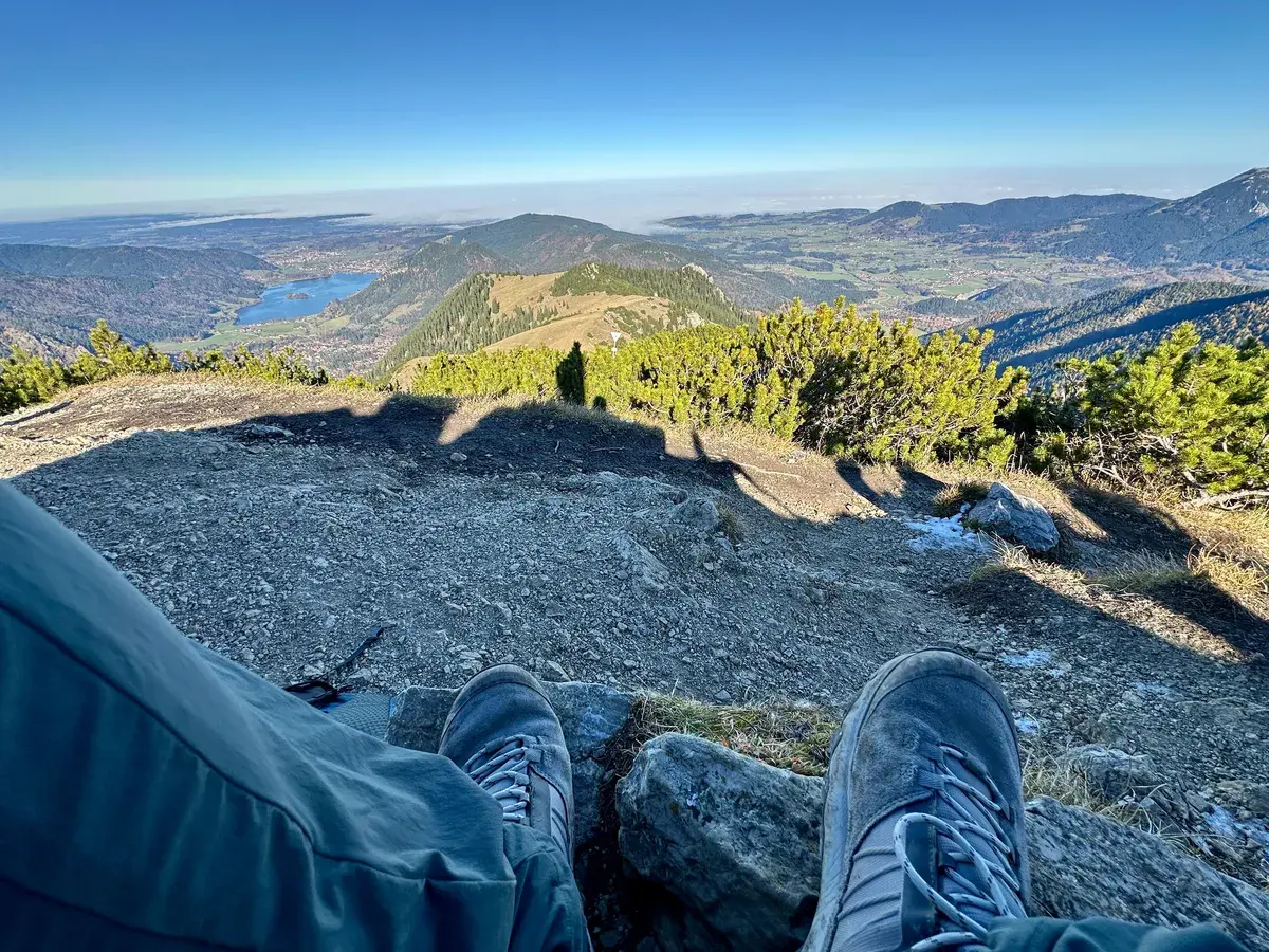 Blick vom Jägerkamp über den Spitzingsee, mit München in der Ferne unter dicken Wolken.