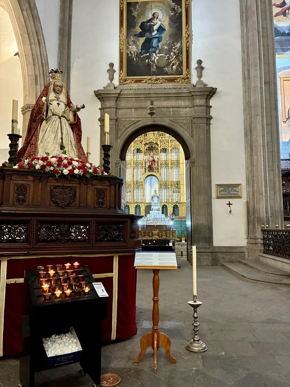 Eine reich verzierte Kirche mit einer religiösen Statue, Kerzenständern und einem imposanten Altar im Hintergrund.
