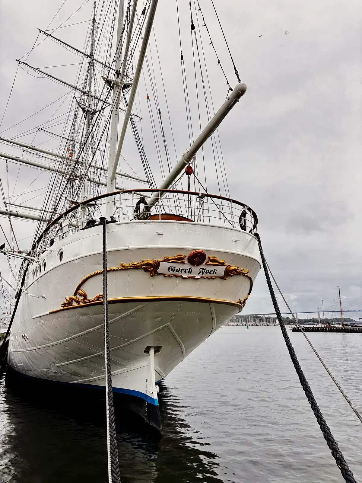 Heck eines weißen Segelschiffs mit dem Namen „Gorch Fock“ im Hafen von Stralsund bei grauem Himmel