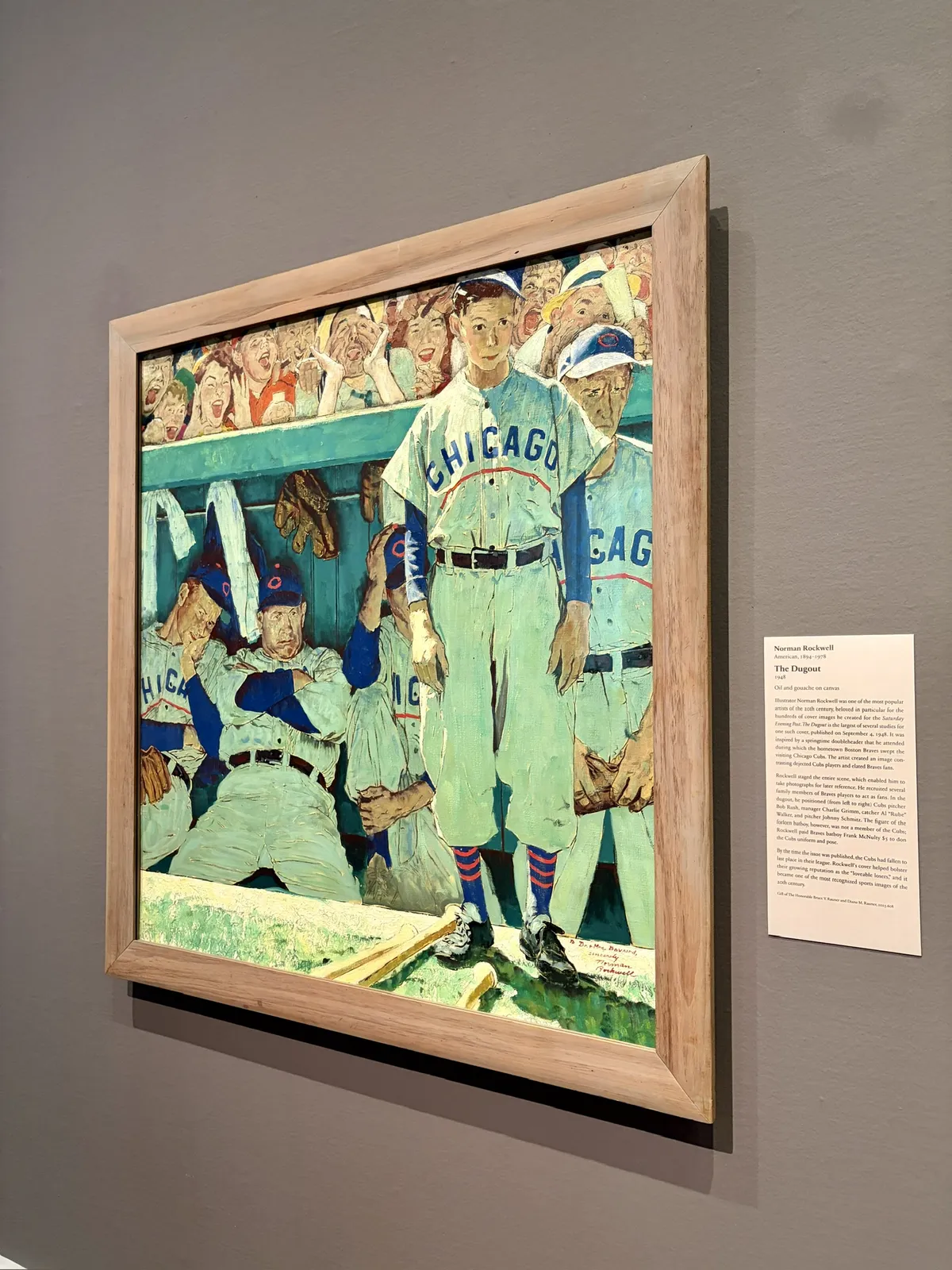 Ein gemaltes Kunstwerk zeigt mehrere Baseballspieler in einer Umkleidekabine. Ein Spieler steht im Vordergrund, gekleidet in ein weißes Trikot mit der Aufschrift "CHICAGO", während andere Spieler im Hintergrund sitzen und zuschauen.